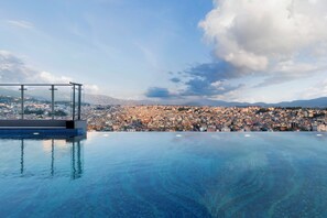 A rooftop infinity pool with a glass railing overlooking a cityscape. - Mercure Kathmandu Sukedhara Heights (Kathmandu)