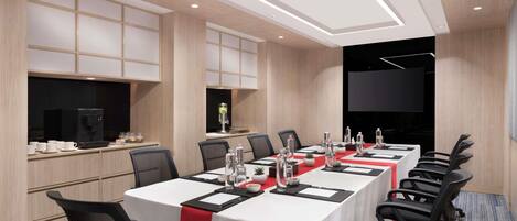 A conference room with a long table, chairs, a coffee machine, and a TV screen.