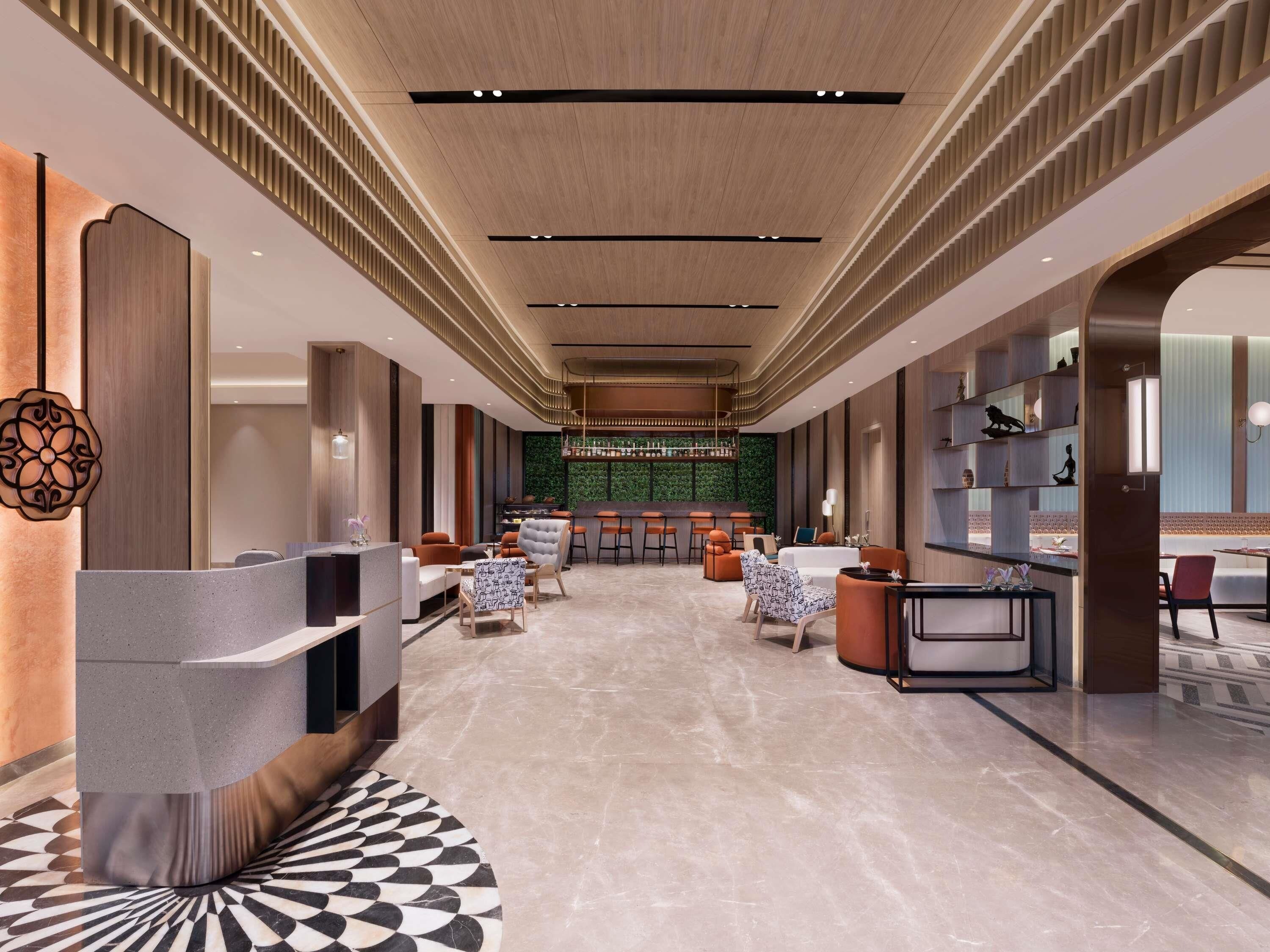 Un moderno vestíbulo de hotel con recepción, zona de estar y bar.