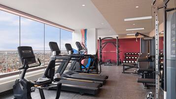 Una palestra con tapis roulant, rack per squat e bilancieri.