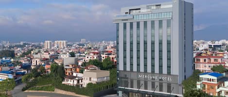 A modern hotel building with a prominent entrance and a view of the surrounding cityscape.
