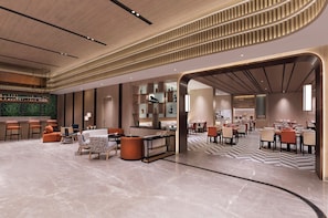 Un hall d’hôtel moderne avec un bar, des espaces aménagés pour s’asseoir et un sol à motifs.