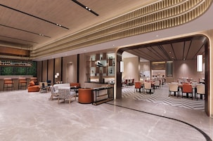 A modern hotel lobby with a bar area, seating arrangements, and a patterned floor.