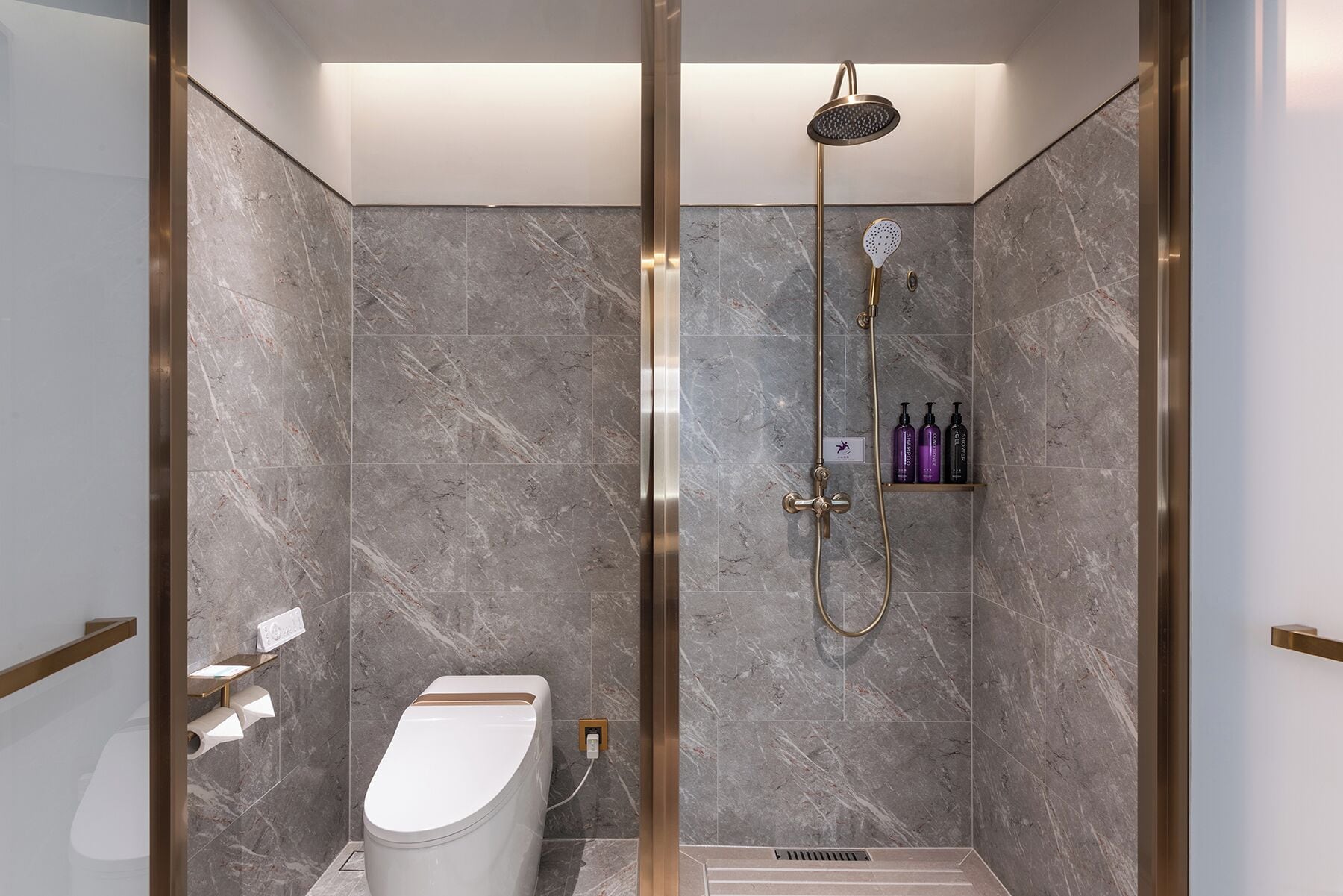 Un baño moderno con ducha, inodoro y paredes de mármol.