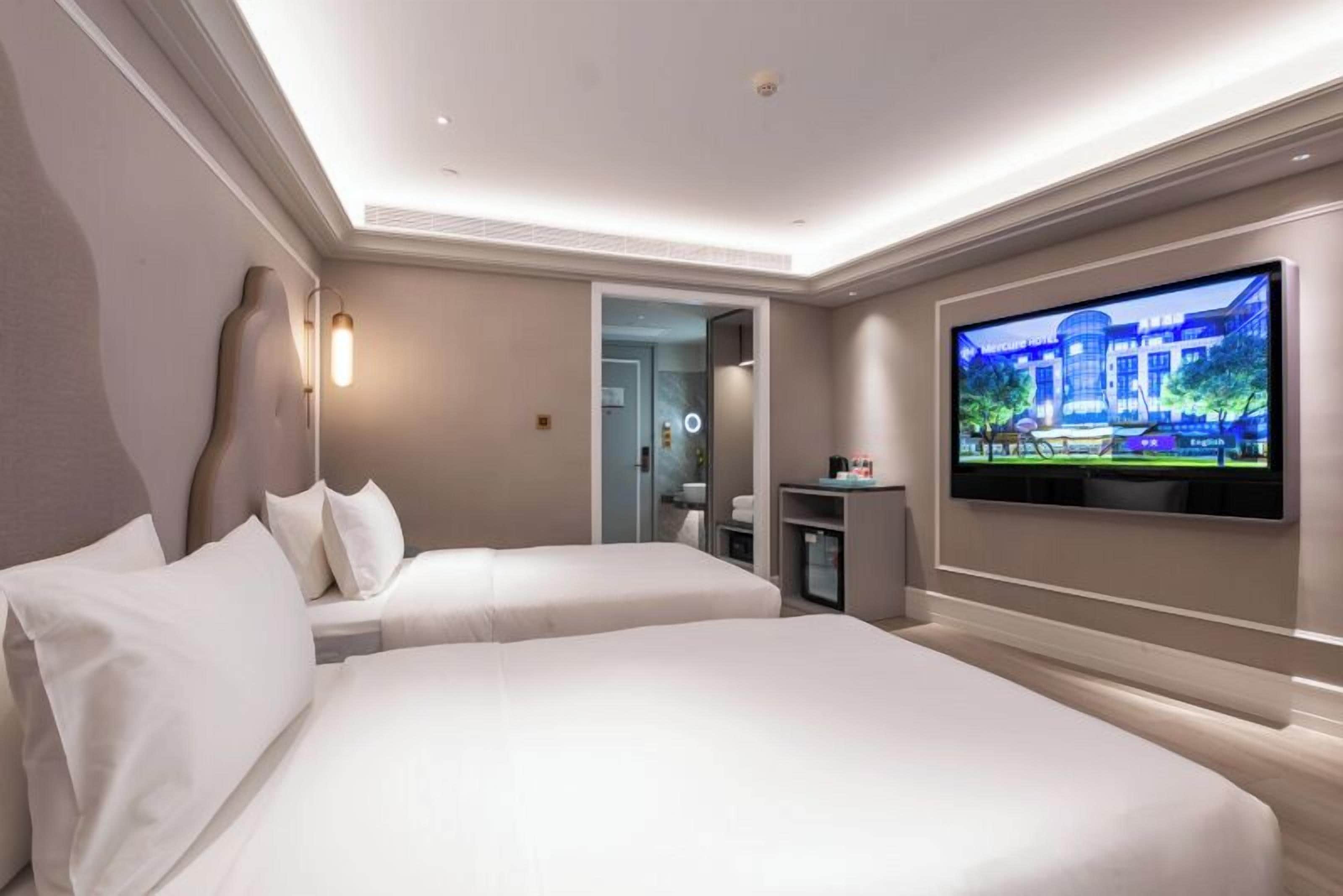 Habitación de hotel con dos camas, televisión y minibar.