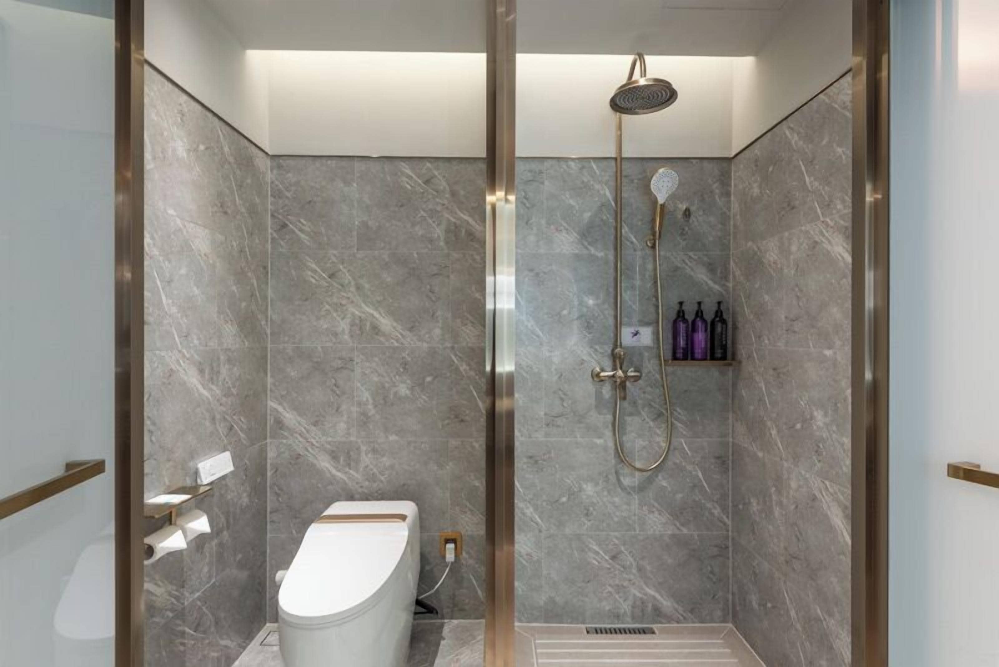 Ein modernes Badezimmer mit Dusche, Toilette und Marmorwänden.
