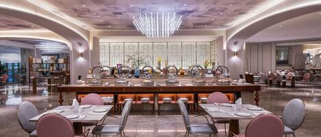 A spacious dining area with a central island, multiple tables, and chairs.