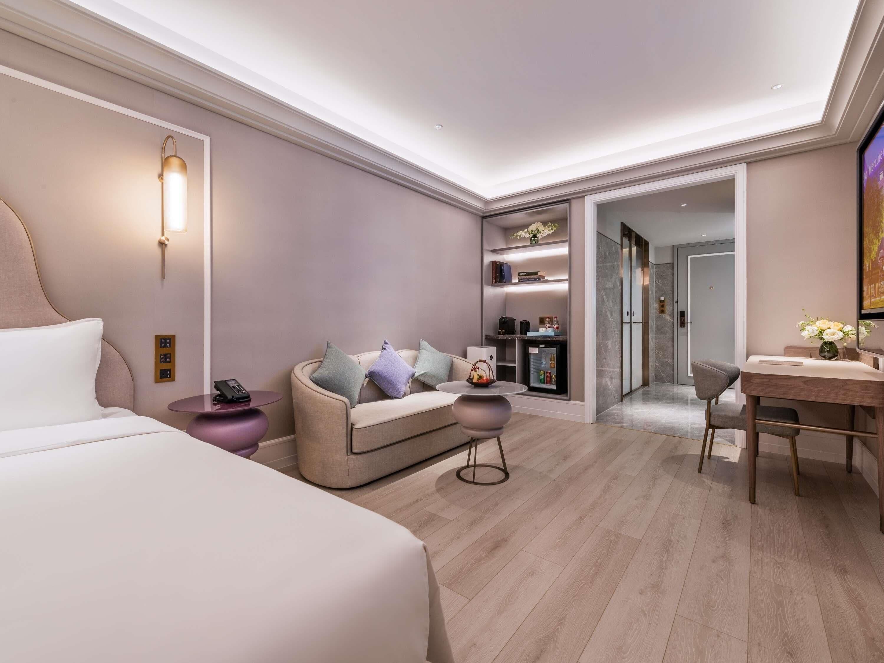 Una habitación de hotel moderna con cama, sofá, mesa de comedor y cocina integrada.