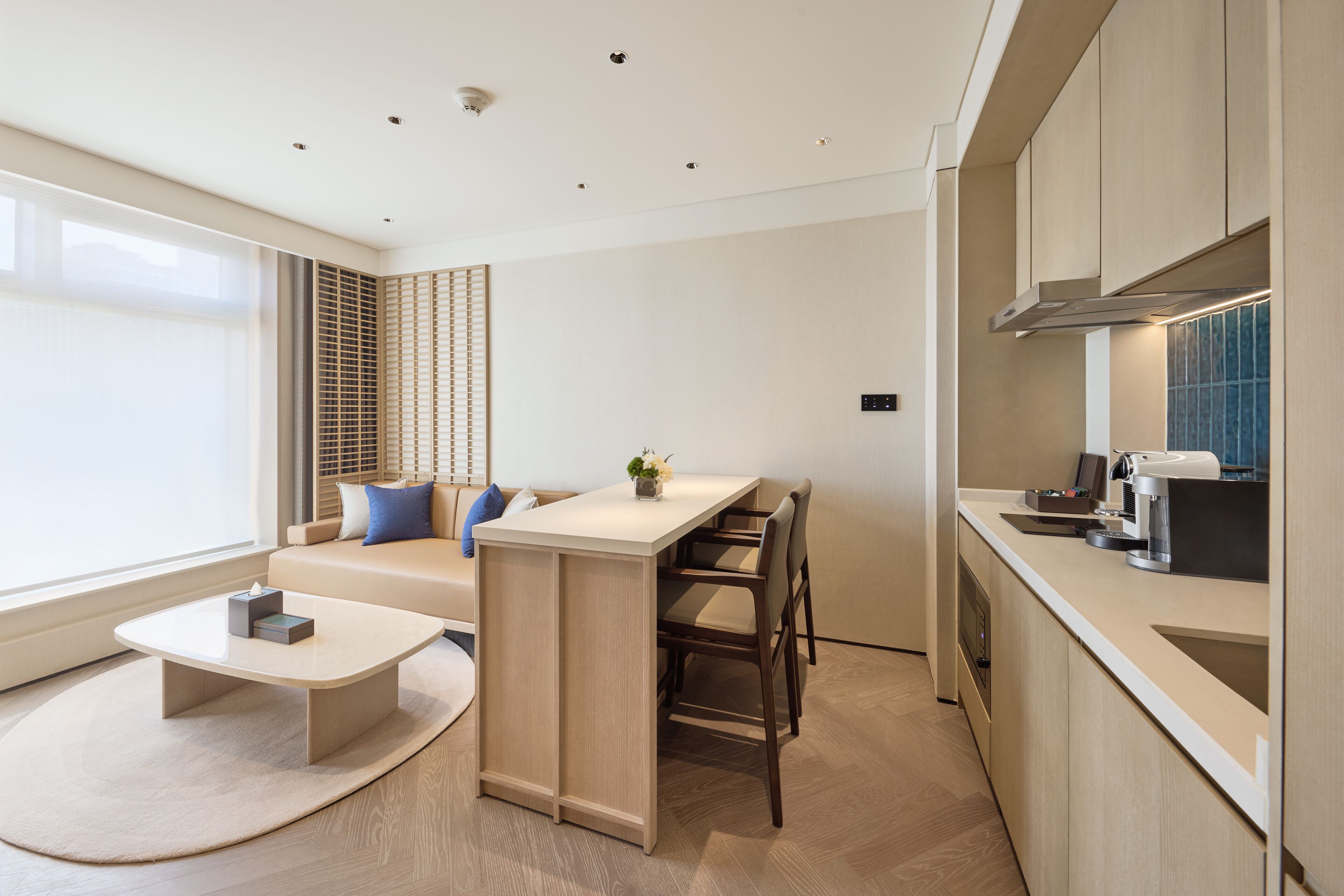 A modern kitchen with a central island, a dining area with a sofa, and a coffee machine.