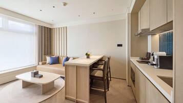 A modern kitchen with a central island, a dining area with a sofa, and a coffee machine.