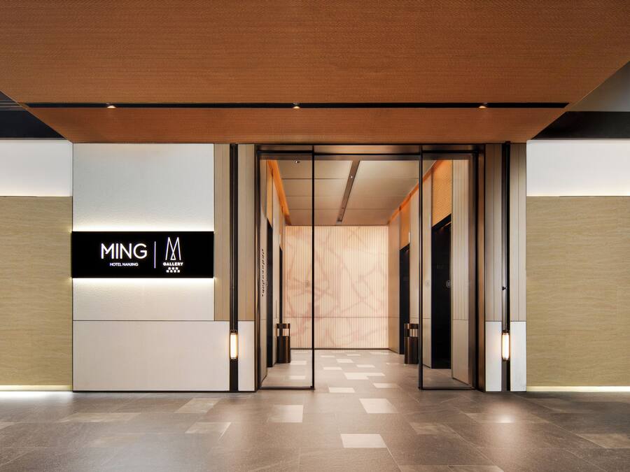 Una entrada de hotel moderna con un cartel que dice 'MING HOTEL NANJING' y una galería.