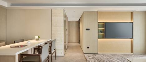 A modern kitchen with a dining area, a large flat-screen TV mounted on the wall, and a patterned rug on the floor.
