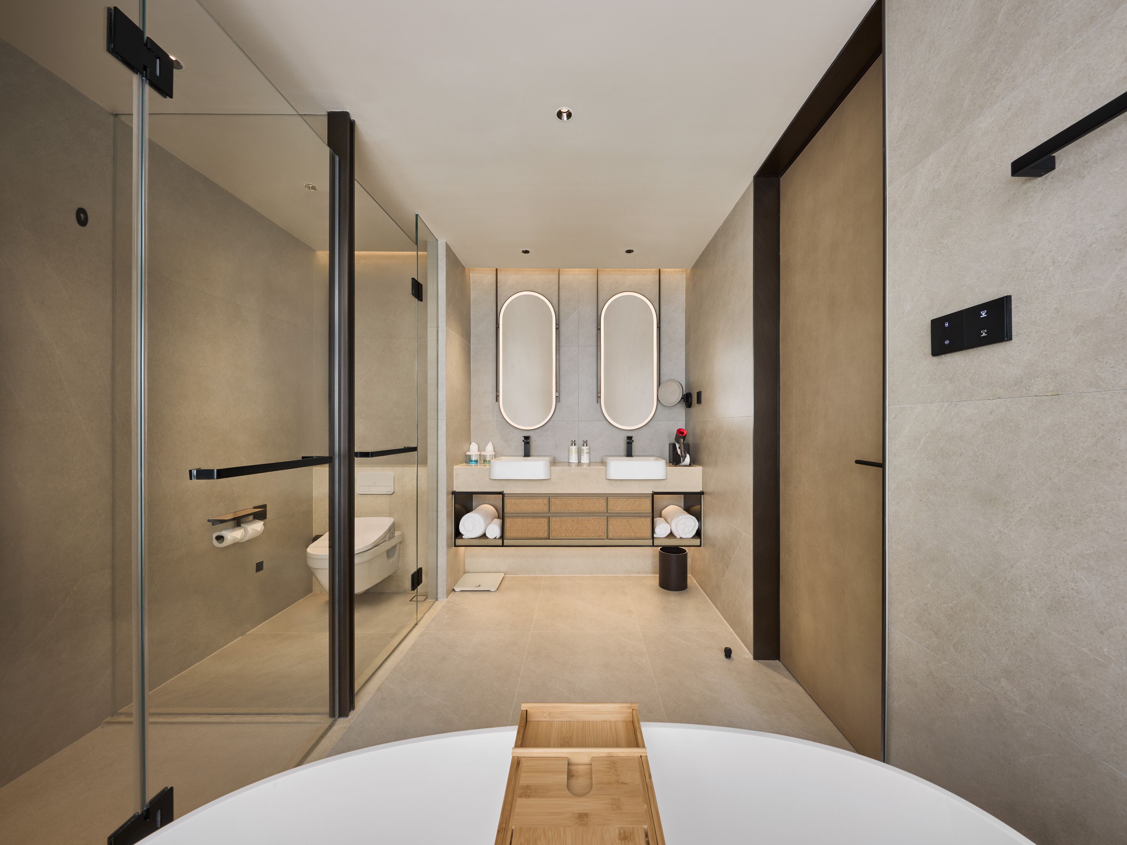 A modern bathroom with a glass shower enclosure, a large mirror, a white sink, and a wooden vanity.