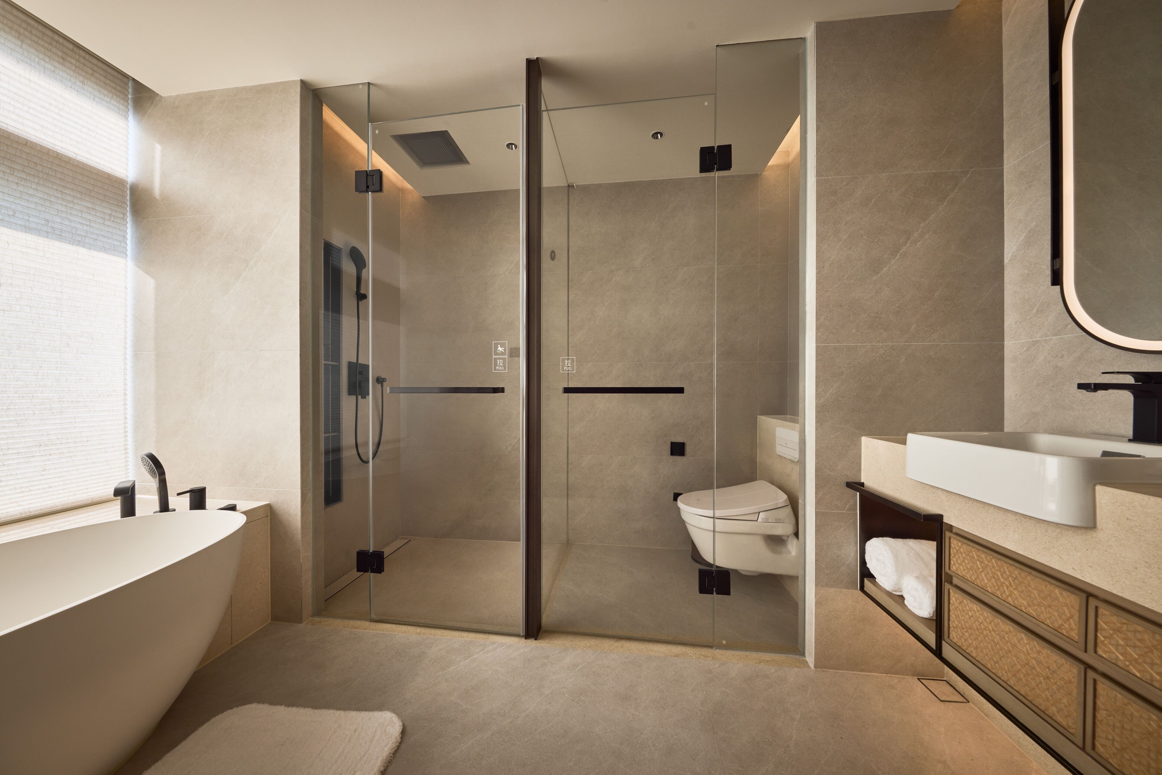 A modern bathroom with a glass-enclosed shower, a freestanding bathtub, and a vanity with a mirror.