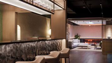 A modern bar area with a marble countertop, bar stools, and a glass display.
