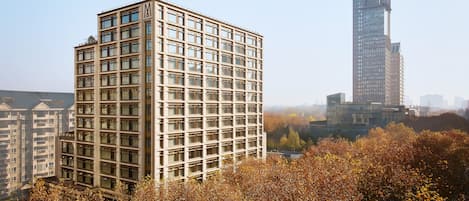 A modern high-rise building with a grid of windows and a prominent 'M' logo on the facade.