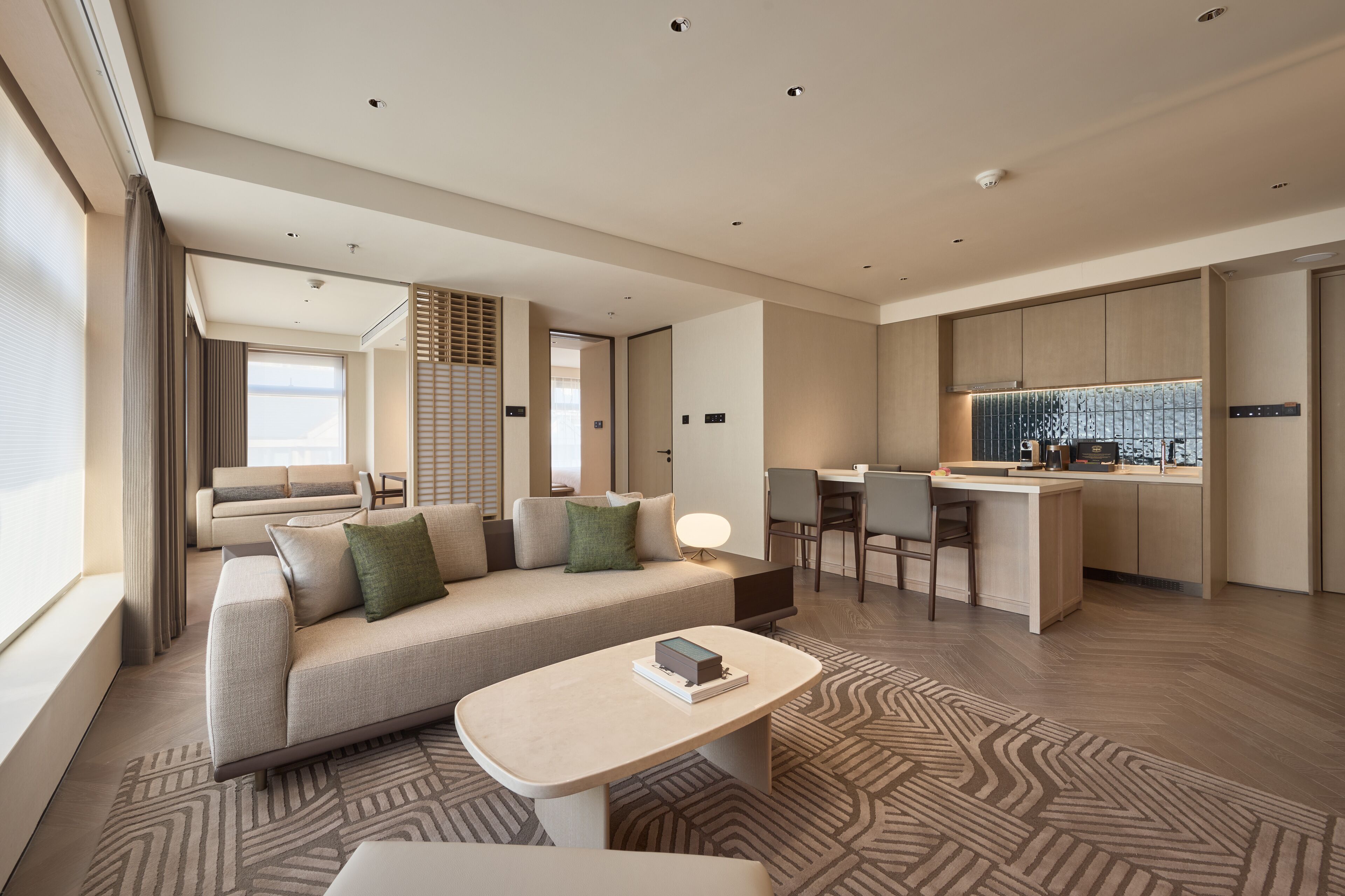 Ein modernes Hotelzimmer mit Sofa, einem kleinen Tisch, einer Küchenzeile und einem Esstisch.