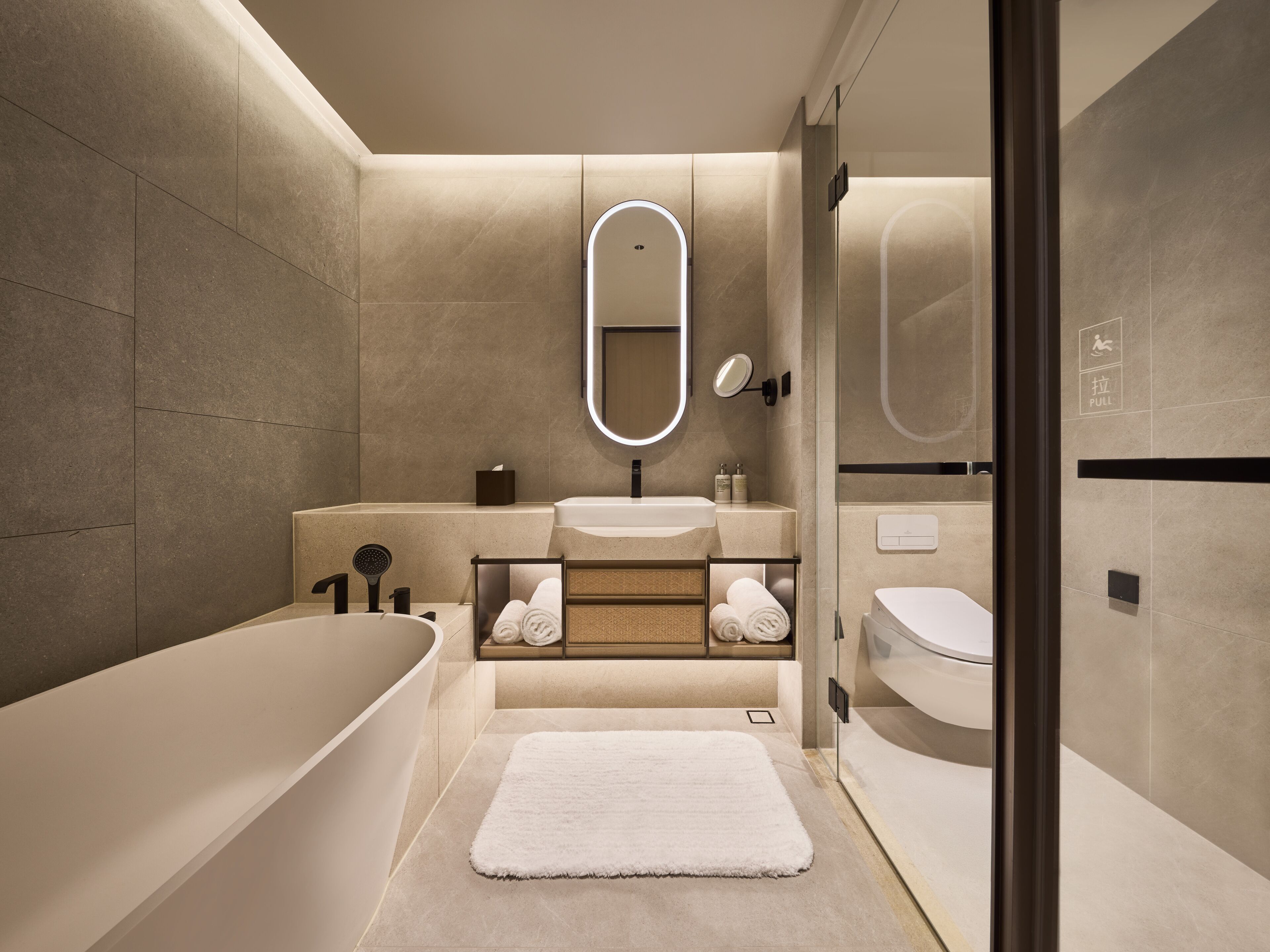A modern bathroom with a freestanding bathtub, a vanity with a mirror, and a toilet.