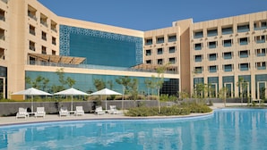 A hotel with a swimming pool, lounge chairs, and umbrellas. - Mövenpick Hotel Waad Al Shamal (Turaif)