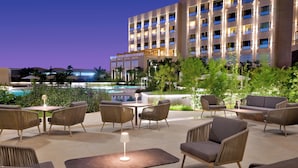 A hotel with outdoor seating, a swimming pool, and a building with multiple balconies. - Mövenpick Hotel Waad Al Shamal (Turaif)
