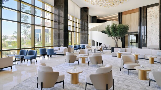 A spacious lobby with large windows, modern seating, and a central staircase. - Mövenpick Hotel Waad Al Shamal (Turaif)