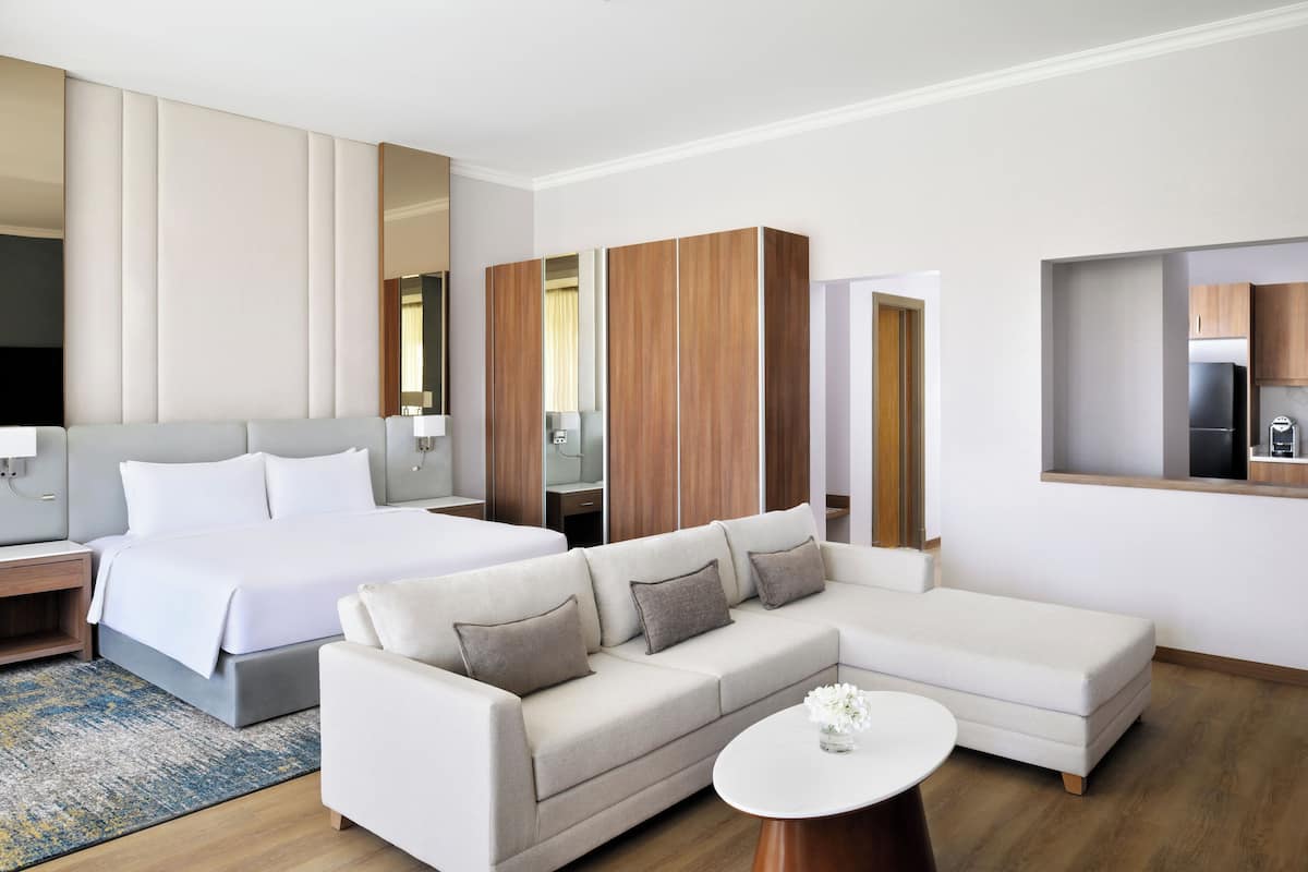 Ein modernes Hotelzimmer mit einem großen Bett, einer Couch, einem kleinen Tisch und einem Kleiderschrank.