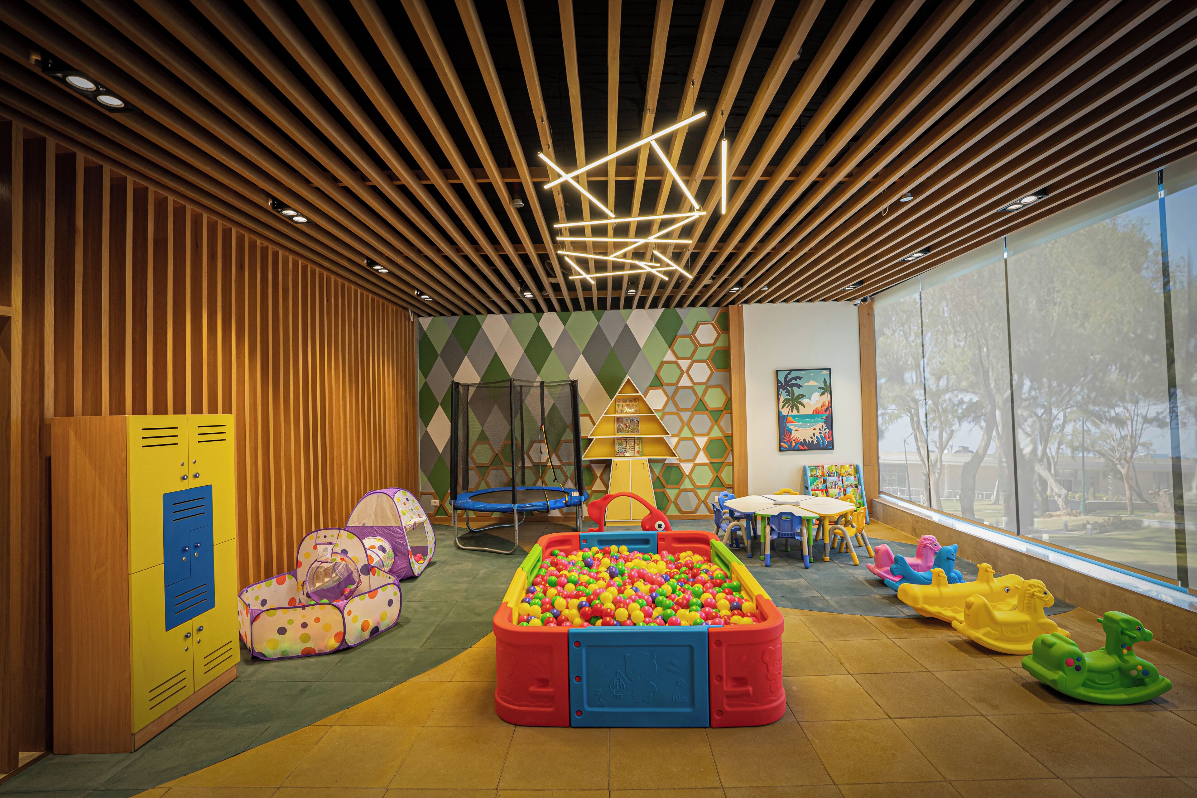 A children's play area with a ball pit, colorful play structures, and a wooden slatted ceiling.