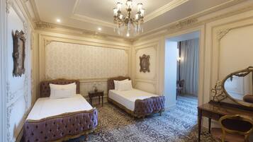A luxurious bedroom with two beds, ornate furniture, and a chandelier.
