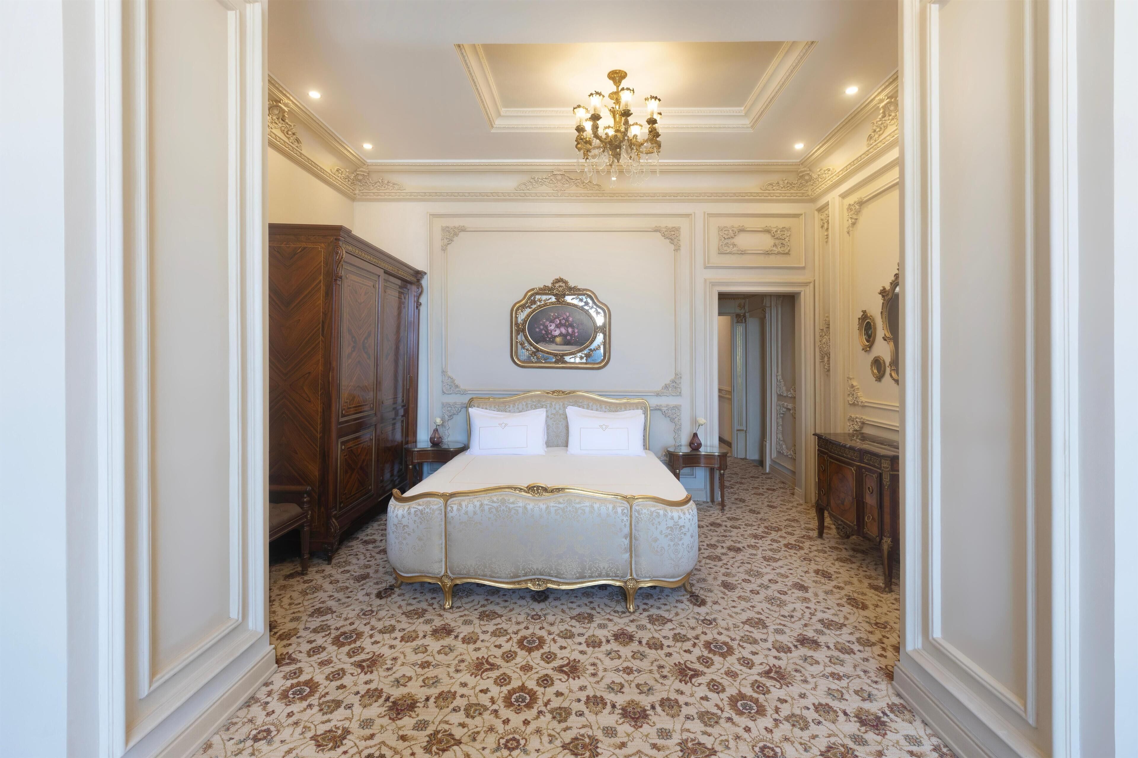 Une chambre spacieuse avec un grand lit, un plafond décoré et un décor classique.