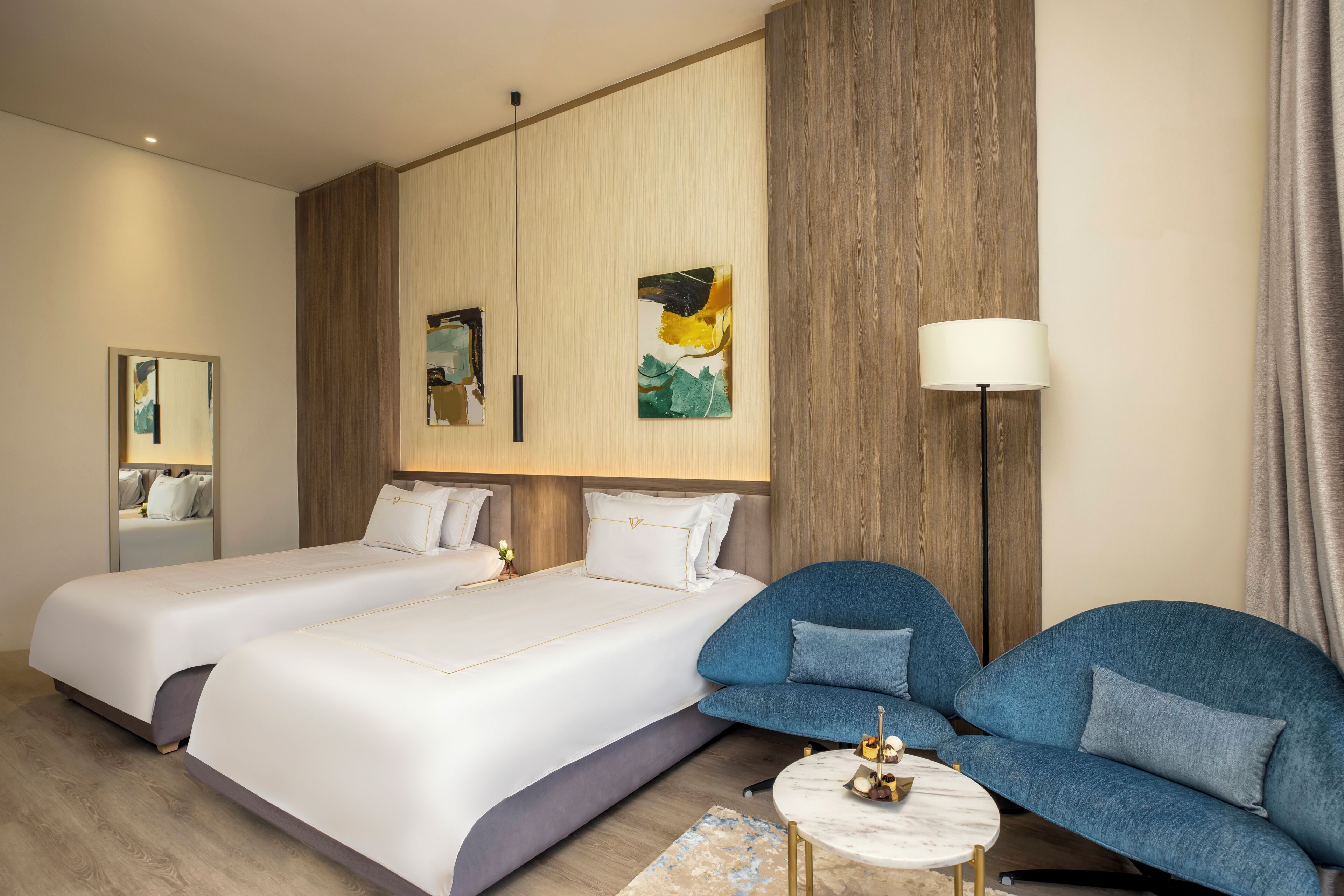 Ett hotellrum med två sängar, en soffa, ett litet runt bord och en lampa.