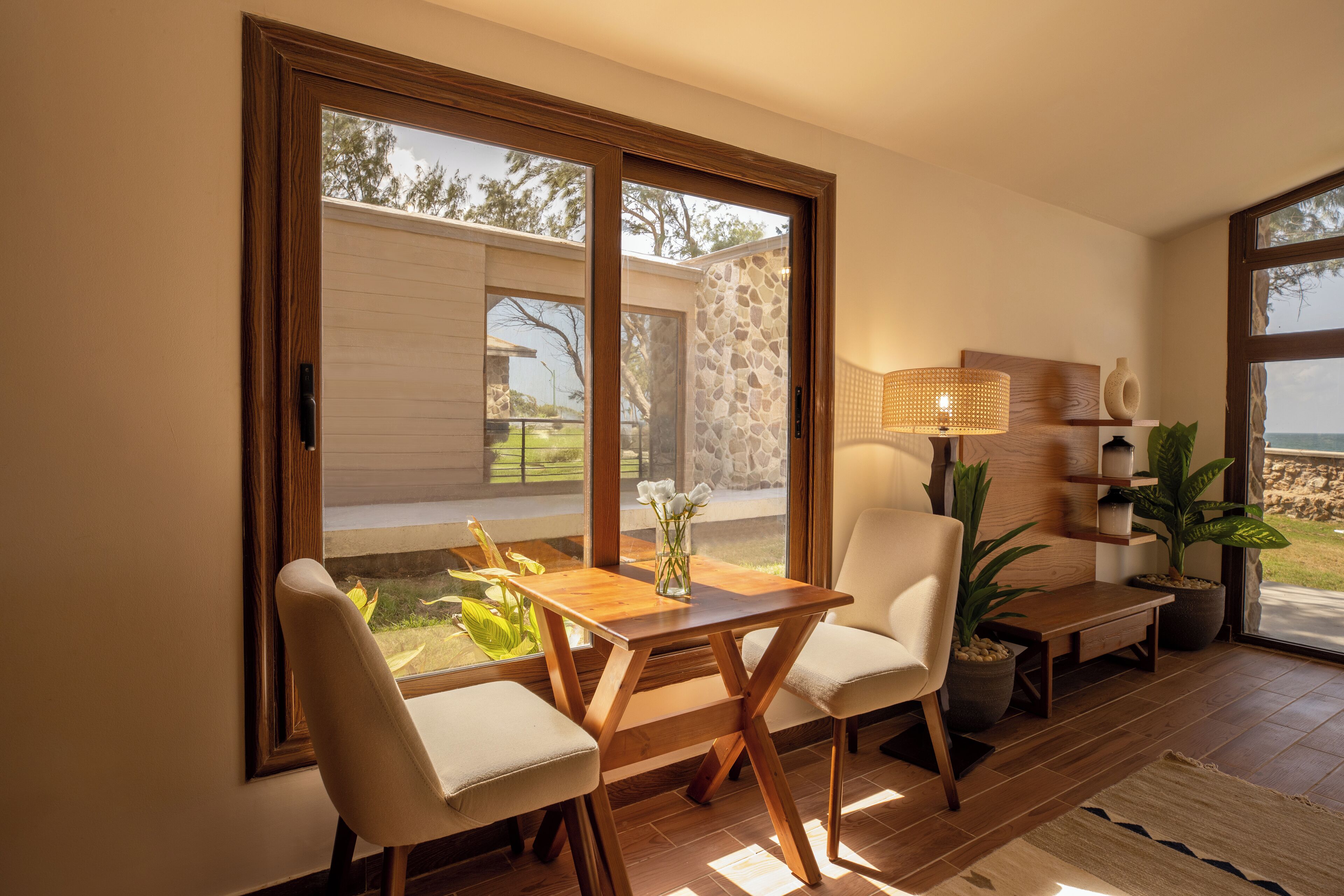 Una sala de estar moderna con una mesa y sillas de madera, ventanas grandes y vistas al exterior.