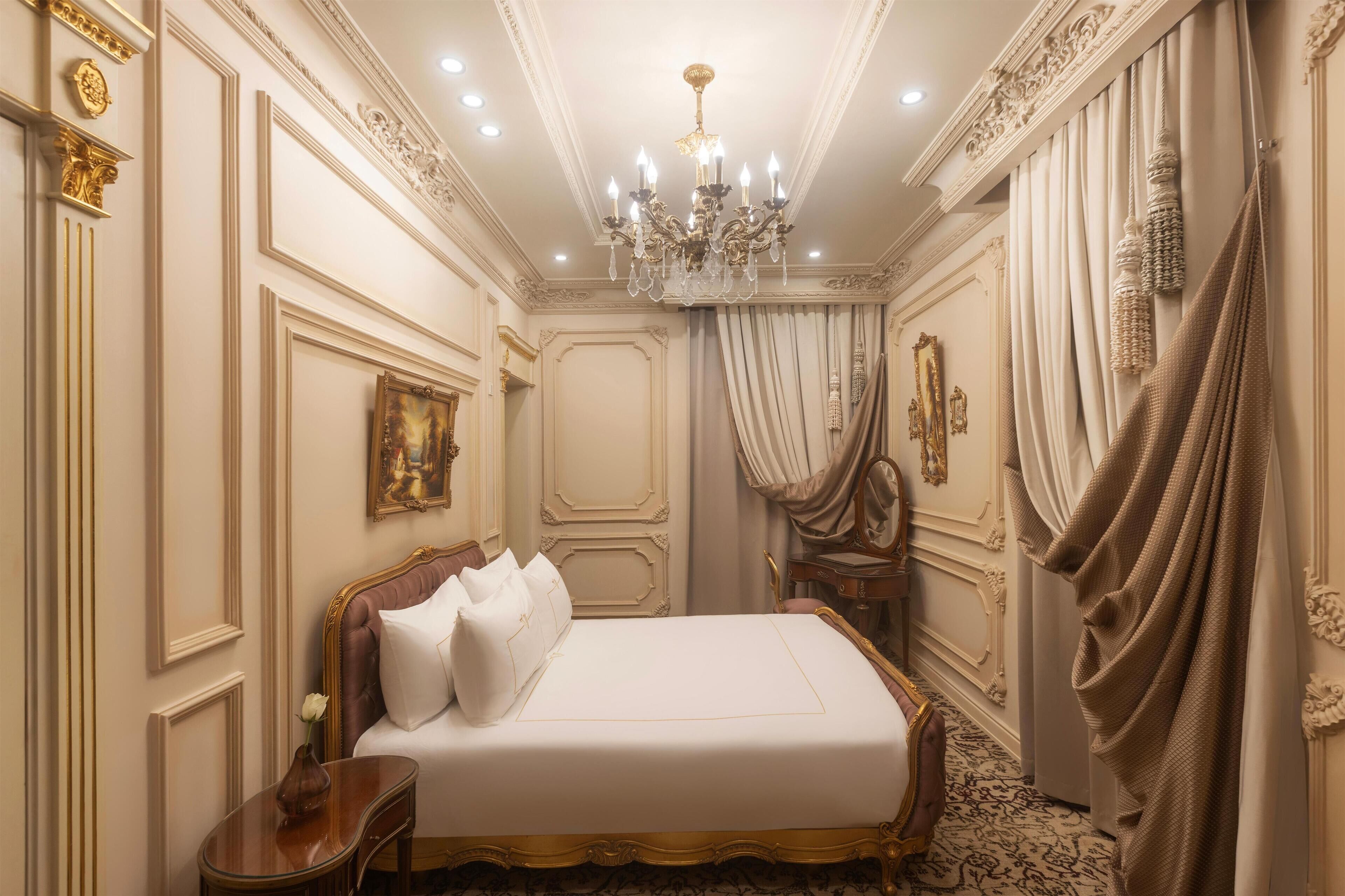 Um quarto luxuoso com uma cama grande, decorações de parede elaboradas e um candelabro.
