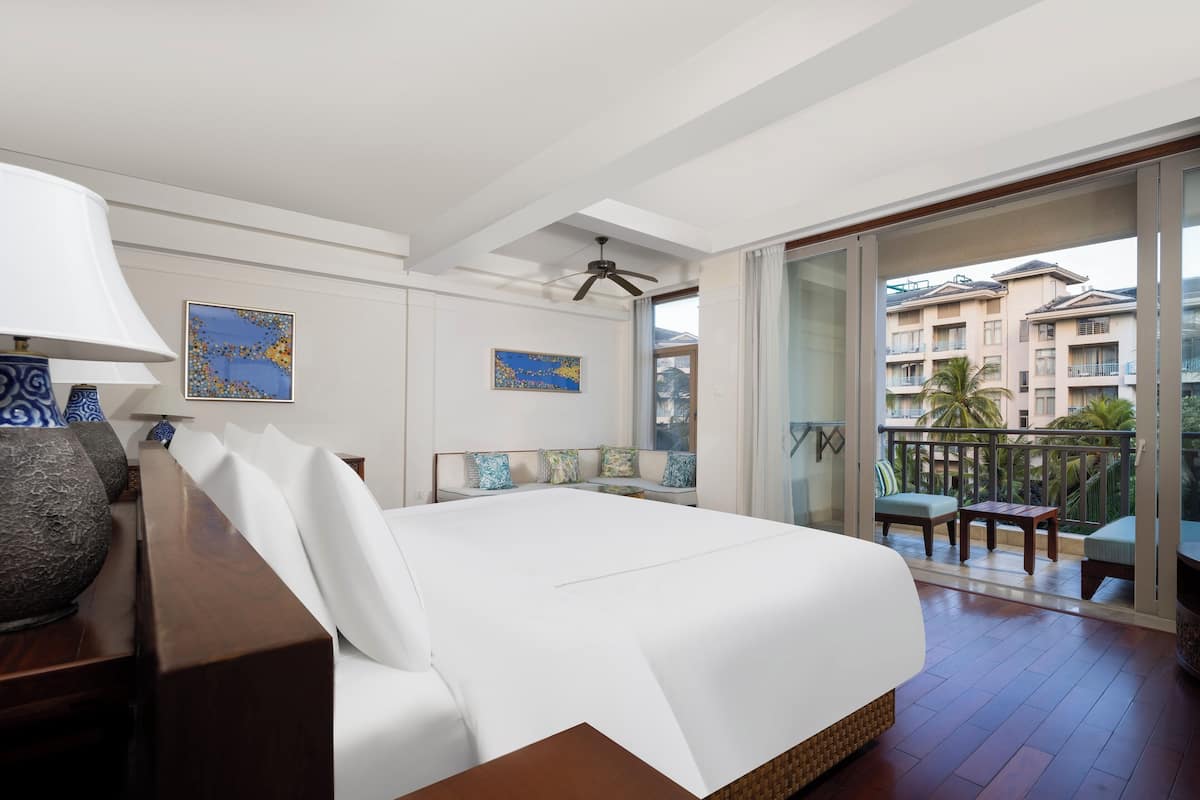 Een hotelkamer met een groot bed, een balkon met zitplaatsen buiten en kunstwerken aan de muur.
