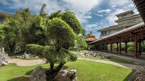 Een traditionele Japanse tuin met een rots, een grote boom en een theehuis.