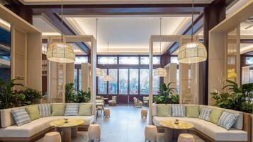 A spacious lobby with a central seating area, large windows, and hanging lamps.
