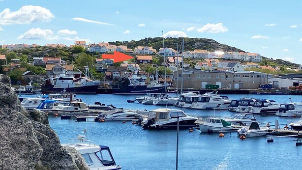 A marina with various boats docked, surrounded by residential buildings and a hilly landscape in the background. - Large villa with sea view in Rönnäng | SE09078 (Rönnäng)