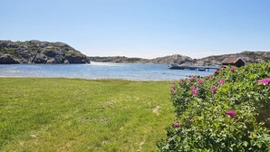 A coastal landscape with a grassy area, a dock, and a small building.