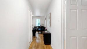 Un pasillo con piso de madera que conduce a un comedor con una mesa y sillas.