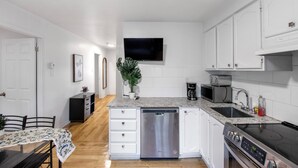 Una cocina moderna con armarios blancos, lavavajillas, estufa y microondas.