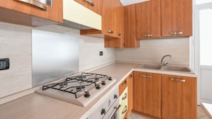 Een moderne keuken met houten kastjes, een gasfornuis en een spoelbak.