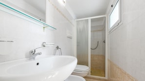 Een moderne badkamer met een groot wastafel, toilet en douchecabine met glazen wanden.
