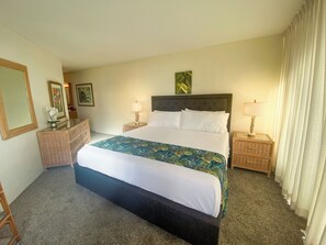 A hotel room with a large bed, two bedside tables with lamps, a dresser, and a mirror.