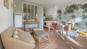 Un salon chaleureux avec un canapé, un pouf et un coin repas comprenant des chaises et une table.