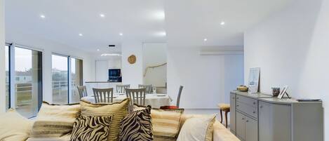 A modern living room with a sofa, dining area, and kitchen.