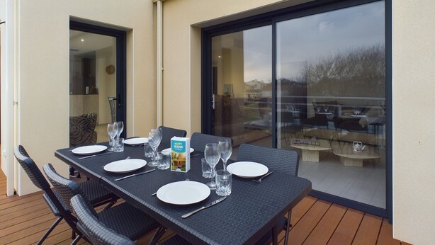 An outdoor dining area with a table set for six, surrounded by chairs, and a sliding glass door leading to a patio. - 350m from the beach, house for 7 with a pool (Bretignolles-sur-Mer)