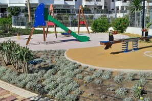 Children can play safely on the slide, seesaw, and swing set in this outdoor play area.