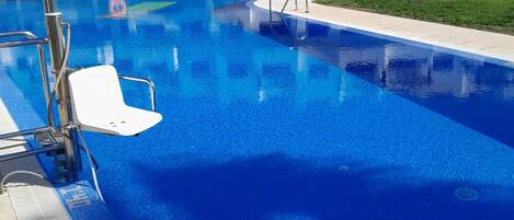 A swimming pool with clear blue water, a white chair, and a lifebuoy.