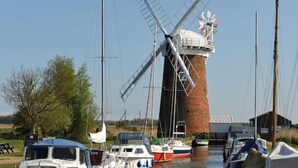 A windmill, boats, and a small building in a rural setting.