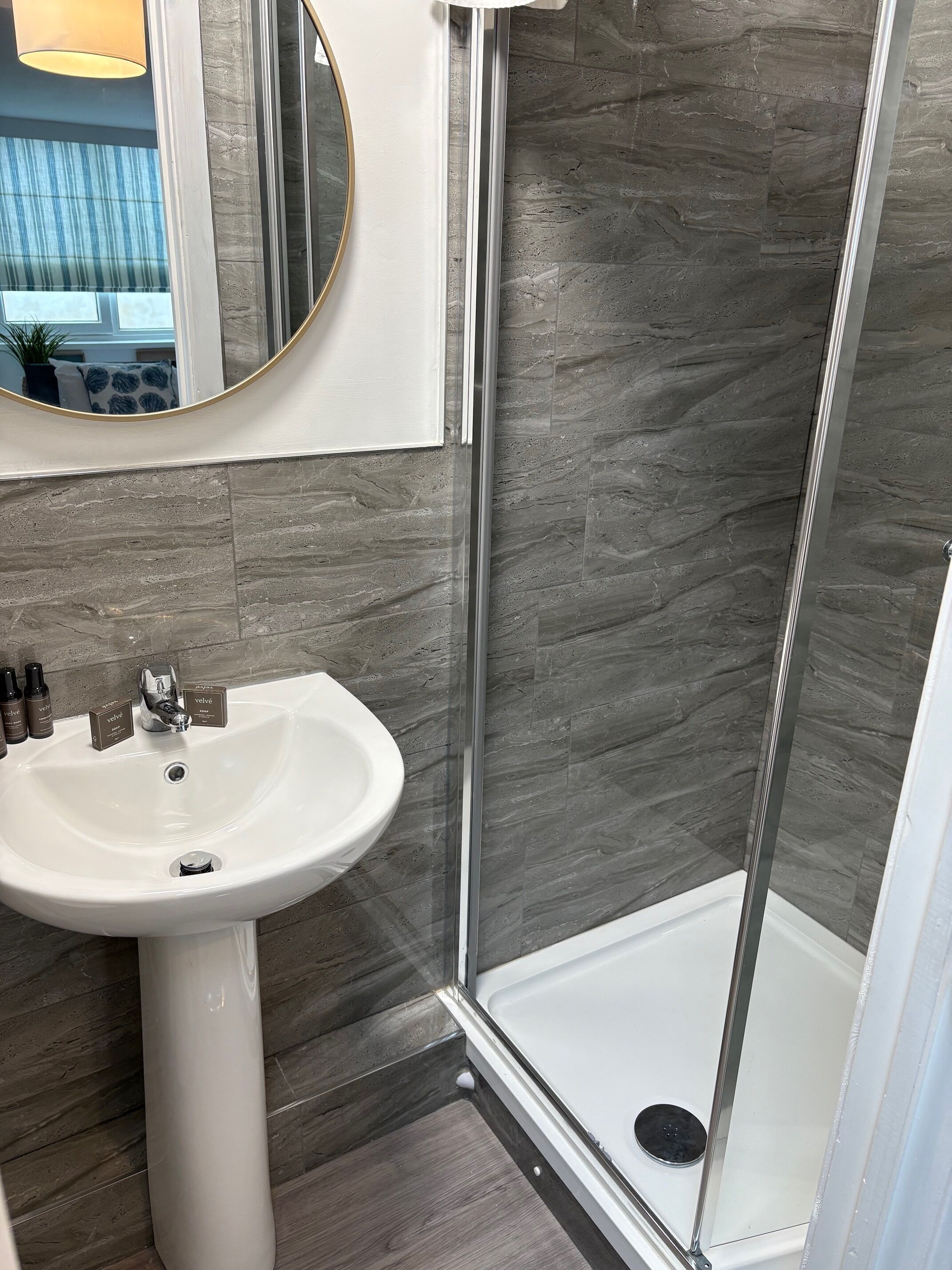 A bathroom with a white sink, a mirror, and a shower area with a glass door.