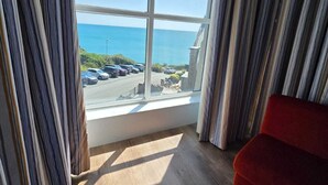Una habitación con un ventanal grande que ofrece vistas al mar y un estacionamiento.